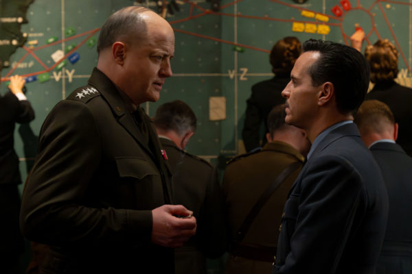 A scene from the film "PRESSURE" (2026), featuring Brendan Fraser as General Dwight D. Eisenhower and Andrew Scott as Captain James Stagg, engaged in a serious conversation against a backdrop of a military map. The image captures the intensity of a pivotal moment in the film.