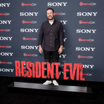 Zach Cregger poses on the red carpet at CinemaCon 2026, standing next to a bold 'RESIDENT EVIL' sign, with a backdrop featuring the Sony Pictures logo.