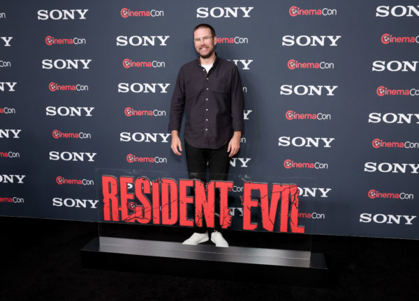Zach Cregger poses on the red carpet at CinemaCon 2026, standing next to a bold 'RESIDENT EVIL' sign, with a backdrop featuring the Sony Pictures logo.