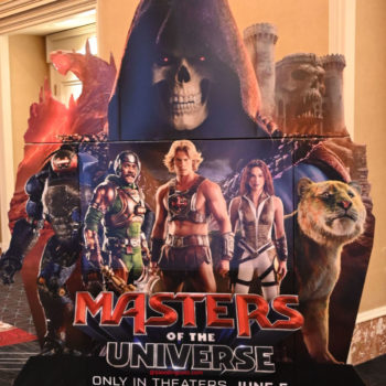 A promotional standee for 'Masters of the Universe', featuring iconic characters like He-Man, Skeletor, and others, set against a vibrant backdrop.