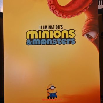 A promotional poster for 'Illumination's Minions & Monsters,' featuring a large, red octopus tentacle and a little yellow Minion character wearing overalls. The background is a gradient of yellow with the release date 'Only In Theaters July 1' displayed at the bottom.