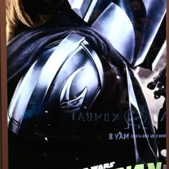 A promotional standee featuring characters from Star Wars: The Mandalorian, showcasing the Mandalorian in armor alongside Grogu, with a colorful background and the text 'THE MANDALORIAN AND GROGU' prominently displayed.