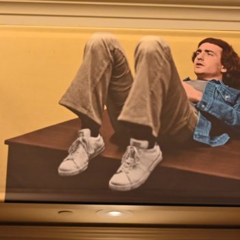 A promotional banner for the film 'Lorne,' directed by Morgan Neville, featuring a young man lounging on a table with his legs crossed, set against a yellow background. The text includes the tagline 'THE MAN WHO MADE SATURDAY NIGHT' and a release date of April 17.