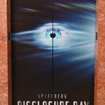 A promotional display for the film 'Disclosure Day' featuring an eye in the center and the tagline 'WE DESERVE TO KNOW.' The display provides details such as the story by Steven Spielberg and the release date of June 12, 2026.