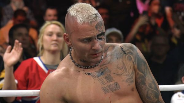 Darby Allin, a professional wrestler with distinctive tattoos and a mohawk hairstyle, appears exhausted after a tough win against Andrade El Idolo. Blood is visible on his lip, and fans can be seen cheering in the background.
