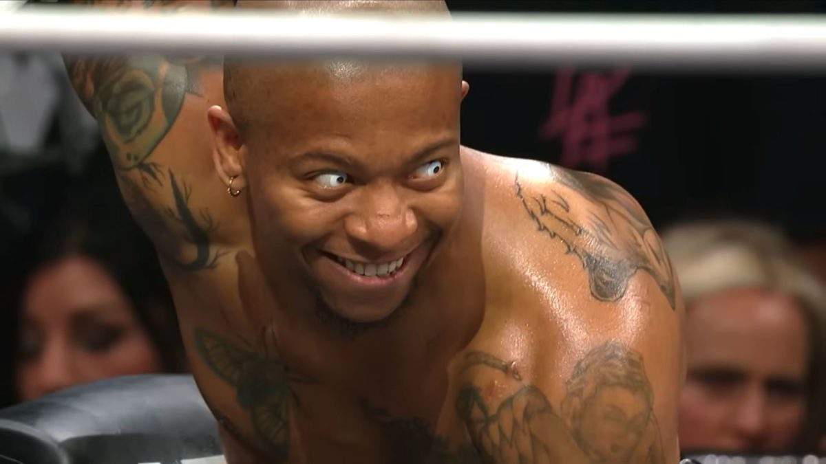 Lio Rush, a professional wrestler, displays an intense expression during a match, showcasing his tattoos and unique personality. The lighting highlights his determined look.