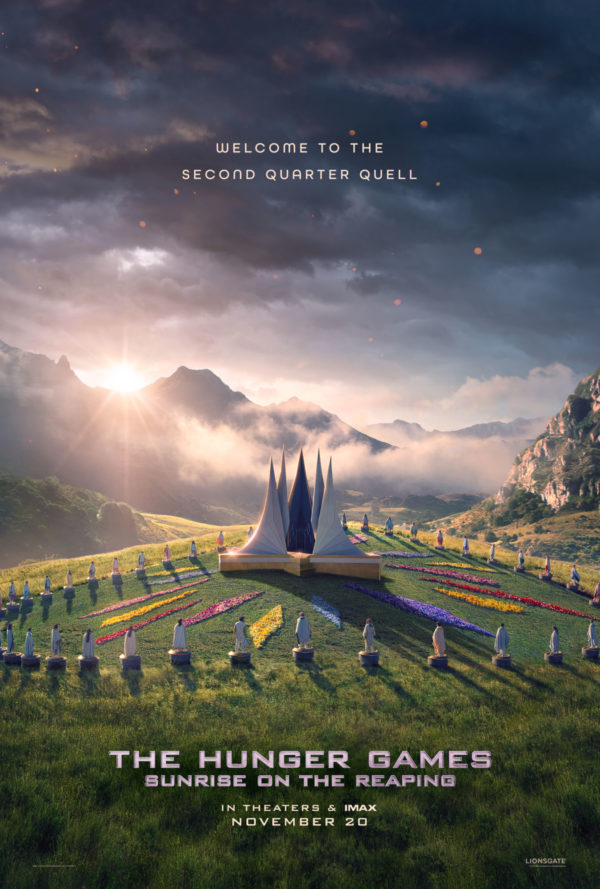A promotional poster for 'The Hunger Games: Sunrise on the Reaping,' featuring a stylized arena surrounded by colorful flowers, with a mountainous backdrop and clouds illuminated by sunrise. The text announces 'Welcome to the Second Quarter Quell' and includes the release date of November 20.