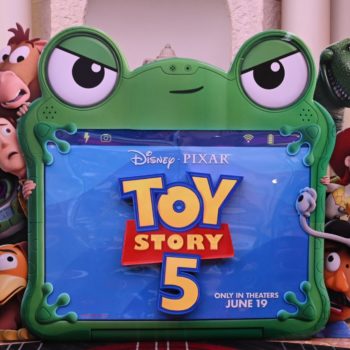 A colorful standee promoting "Toy Story 5," featuring the movie's logo and popular characters like Woody, Buzz Lightyear, and Jessie, set against a vibrant background. The standee announces the film's release date of June 19.