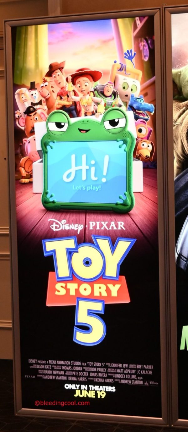 A colorful standee promoting "Toy Story 5" featuring beloved characters from the franchise, along with a greeting from a cartoon device that says "Hi! Let's play!" The standee is displayed at CinemaCon 2026.